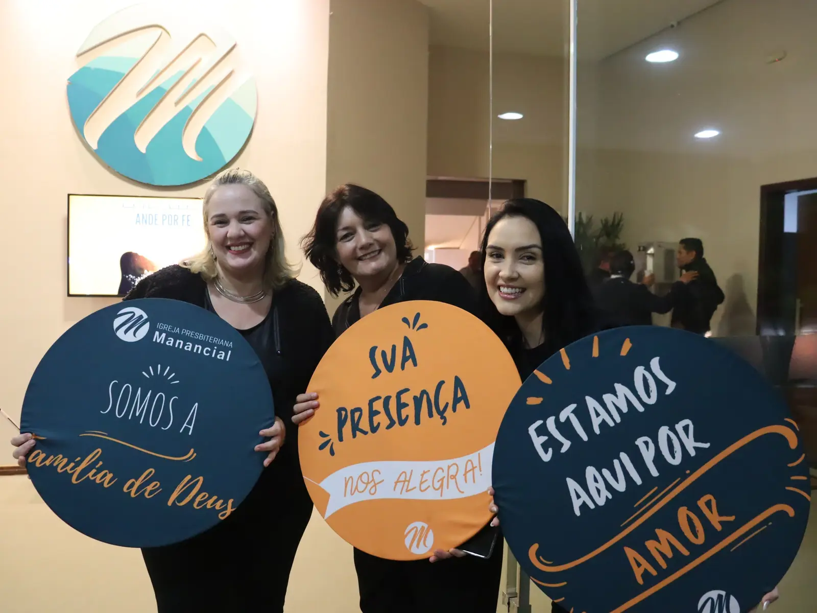 Equipe de recepção com as placas "Somos a família de Deus"